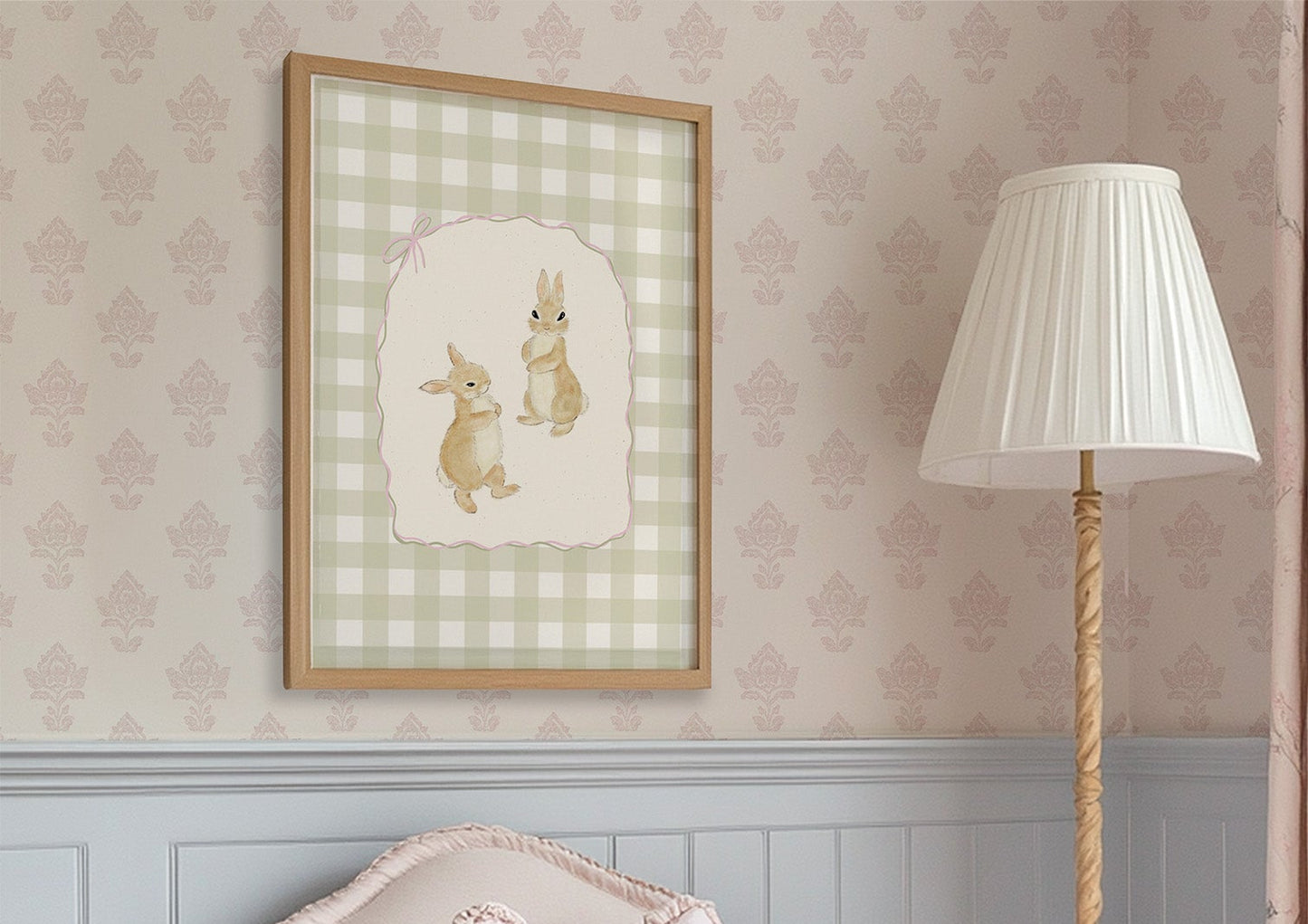 Pink armchair with a white pillow, framed artwork, and standing lamp in a room with patterned wallpaper.