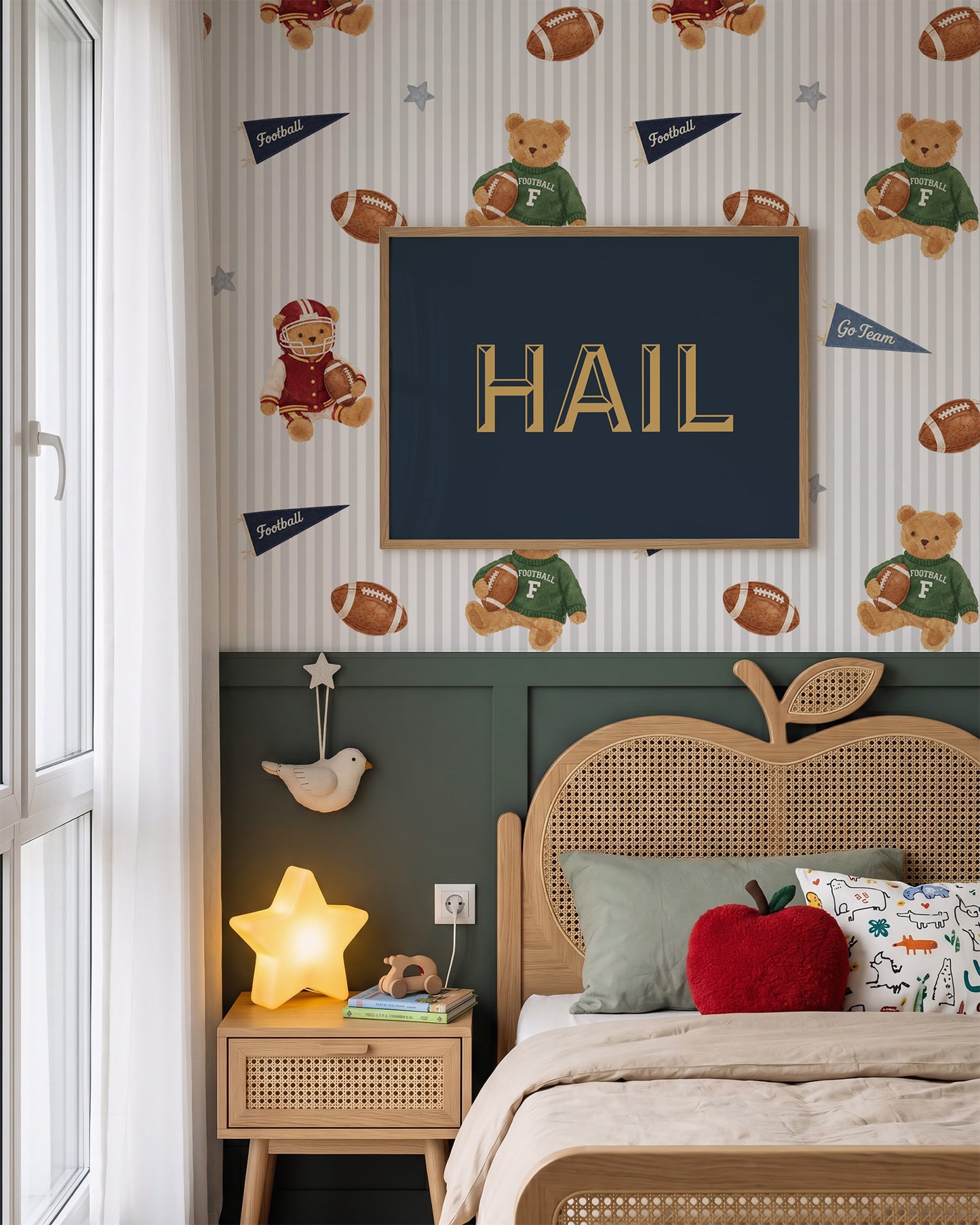 A styled children's bedroom featuring sports-themed wallpaper with teddy bears, footballs, and pennants, a dark green wainscoted wall, a wooden bed frame, and a central framed sign reading 'HAIL'.