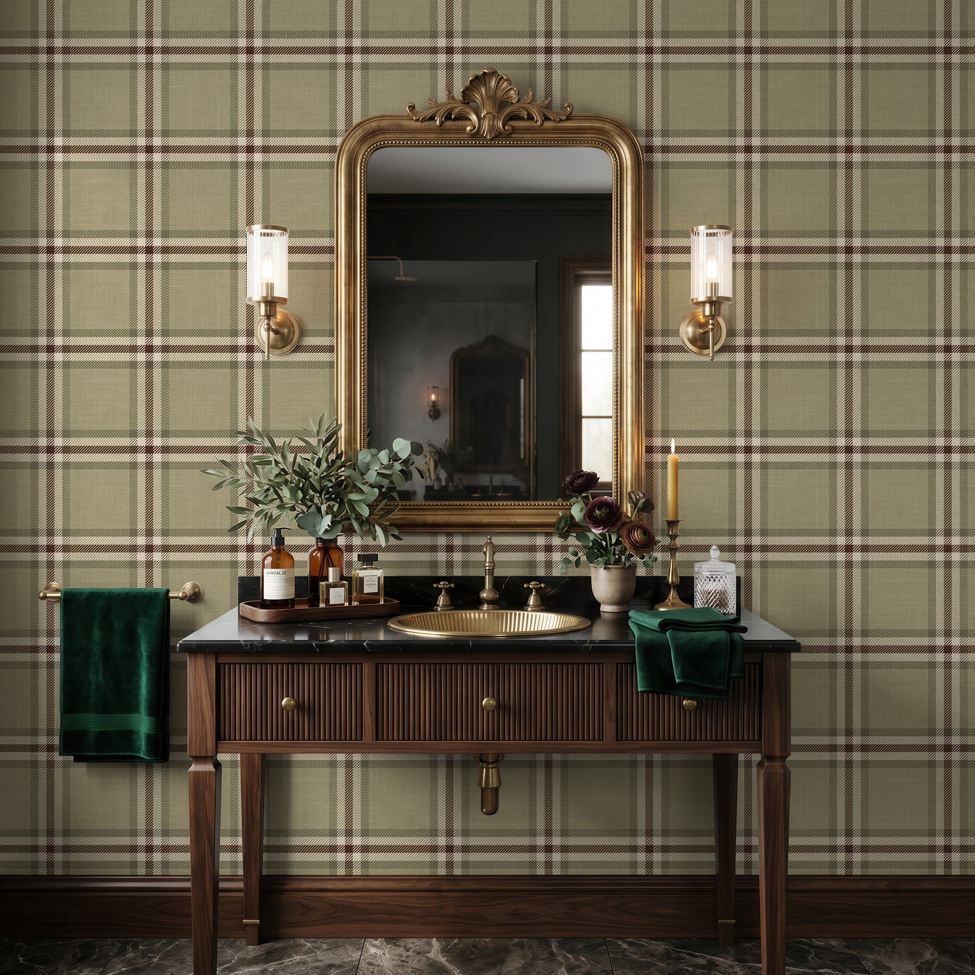 A styled bathroom vanity in a real interior setting, featuring a dark wood console table with a brass sink and fixtures, a large ornate gold mirror, wall sconces, green plaid wallpaper, and green towels and botanical decor.