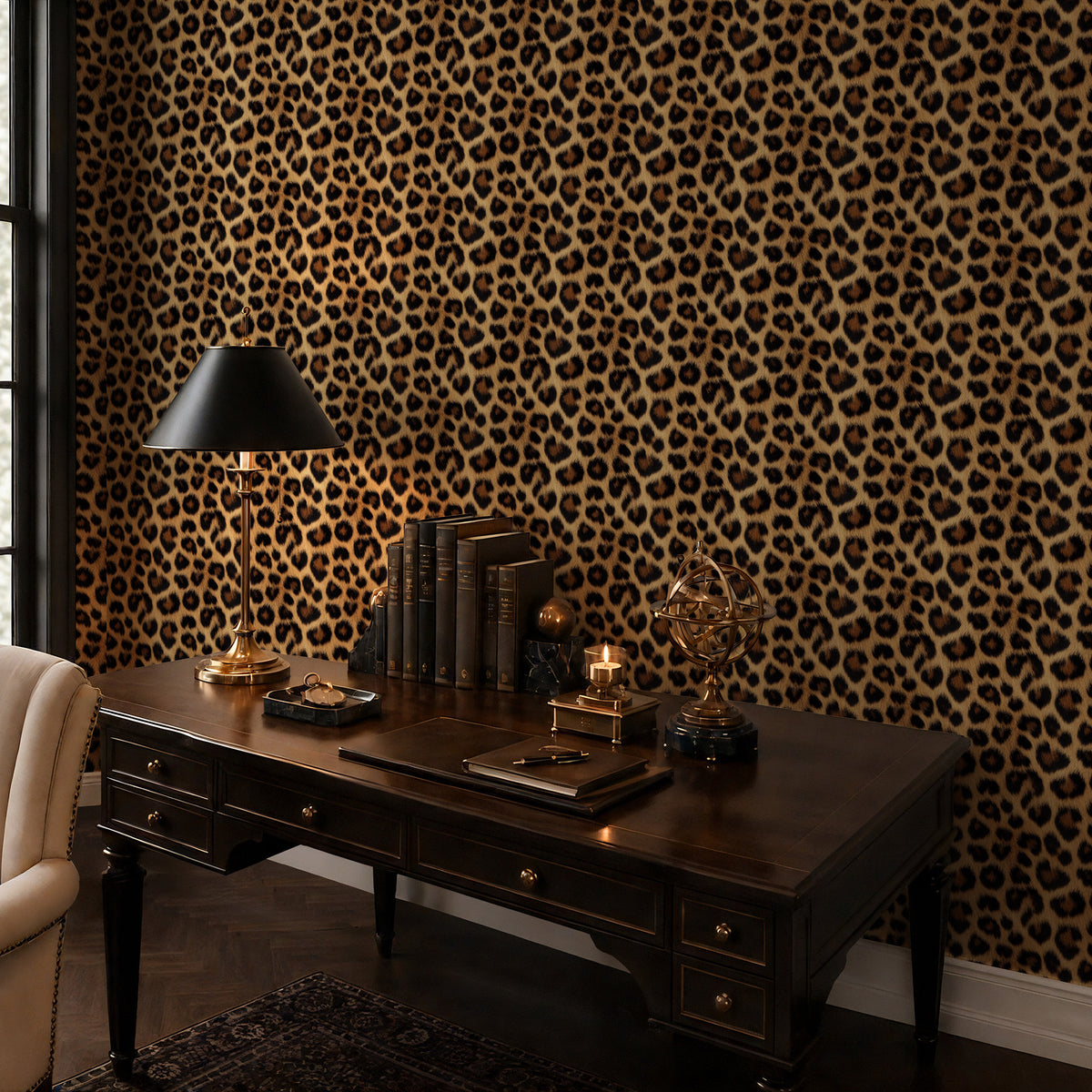 A dark wood writing desk in a styled room, set against a wall covered in brown and black leopard print wallpaper. A black lamp, books, and decorative objects sit on the desk, with a cream chair partially visible on the left.